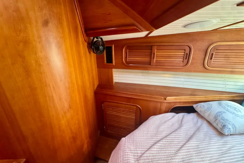 Symphony V Yacht Photos Pics Wood-paneled cabin interior of 1999 Hinckley Sou'wester 52 yacht with bed and fan.