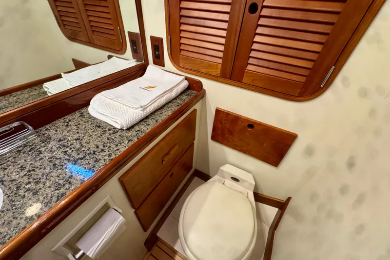 Symphony V Yacht Photos Pics Hinckley Sou'wester 52 yacht bathroom, featuring granite countertop, wooden cabinetry, and elegant fixtures.