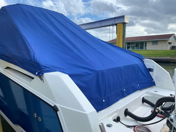  Yacht Photos Pics Hussar Skamander 920 Explorer MAX 2022 boat with blue cover docked by a house.