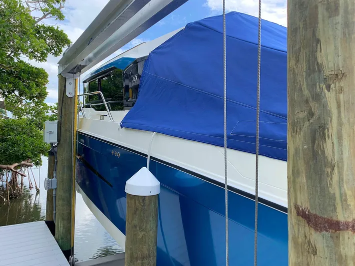  Yacht Photos Pics 2022 Hussar Skamander 920 Explorer MAX boat with blue cover docked by wooden posts.