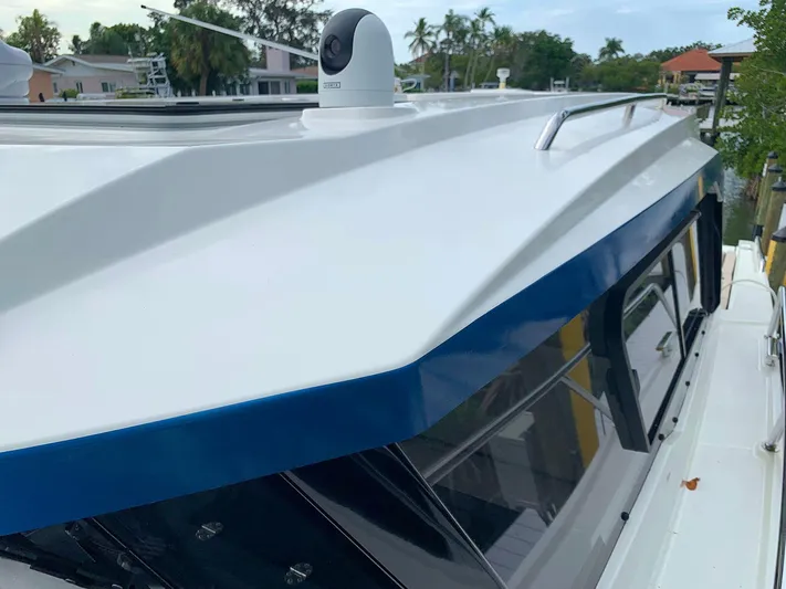 Yacht Photos Pics 2022 Hussar Skamander 920 Explorer MAX boat roof with camera, docked near tropical homes.