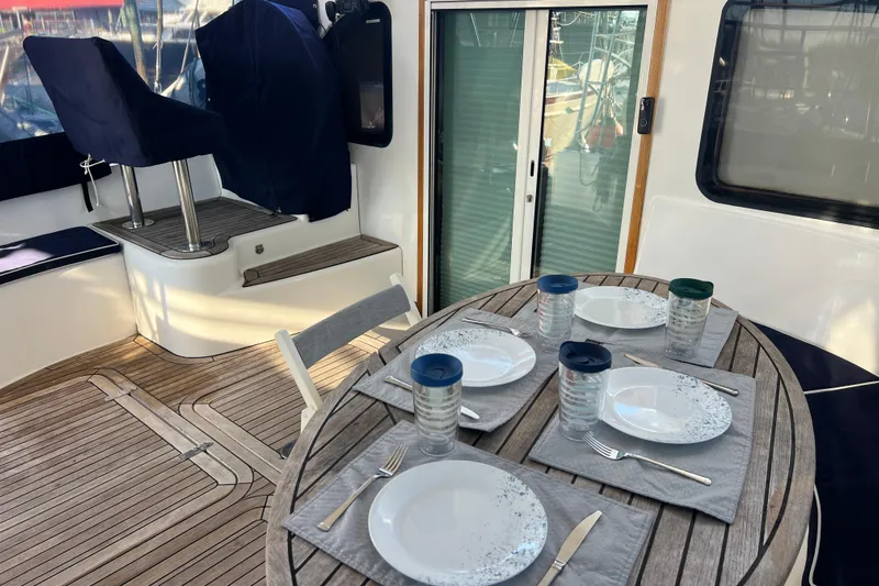 Evolution Yacht Photos Pics Outdoor dining setup on 2011 Privilege 495 yacht with wooden deck and cushioned seating.