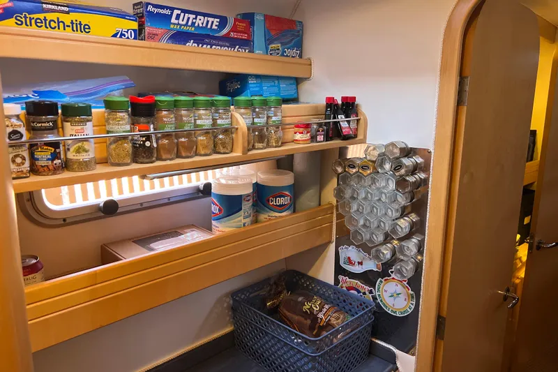 Evolution Yacht Photos Pics Kitchen storage with spices, cleaning supplies, and food items in a Privilege 495 yacht, 2011 model.