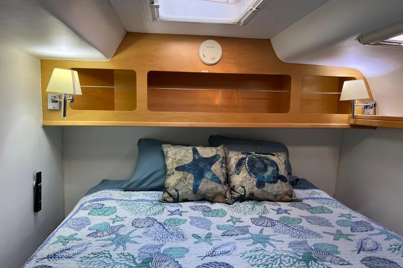 Evolution Yacht Photos Pics Cozy cabin interior of 2011 Privilege 495 yacht with nautical-themed bedding and wooden shelving.