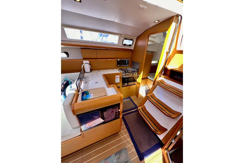 Jenni Yacht Photos Pics Interior of 2015 Jeanneau Sun Odyssey 409 sailboat with modern kitchen and wooden finishes.