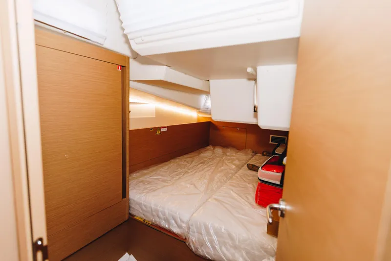 Valinore Yacht Photos Pics 2023 Jeanneau Sun Odyssey 490 cabin interior with cozy bed and wooden finish.