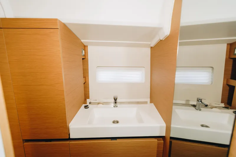 Valinore Yacht Photos Pics Modern bathroom interior of 2023 Jeanneau Sun Odyssey 490 yacht, featuring sleek sink and wood cabinetry.