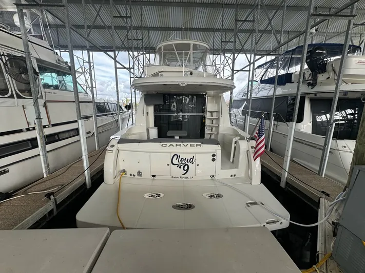 Cloud 9 Yacht Photos Pics 2004 Carver 56 Voyager yacht docked, rear view with American flag, under covered marina.