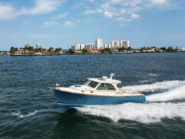  Yacht Photos Pics 2013 Hinckley Talaria 34 cruising on a sunny day near coastal cityscape.