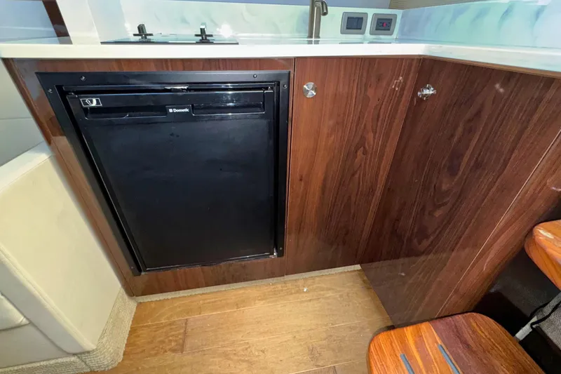  Yacht Photos Pics 2017 Sea Ray Sundancer 350 Coupe interior with wood cabinetry and compact fridge.