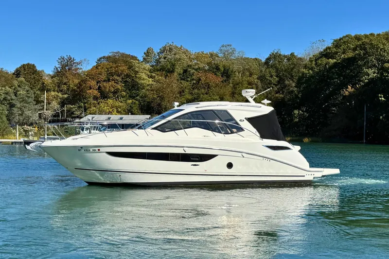  Yacht Photos Pics 2017 Sea Ray Sundancer 350 Coupe cruising on a serene lake with lush trees.