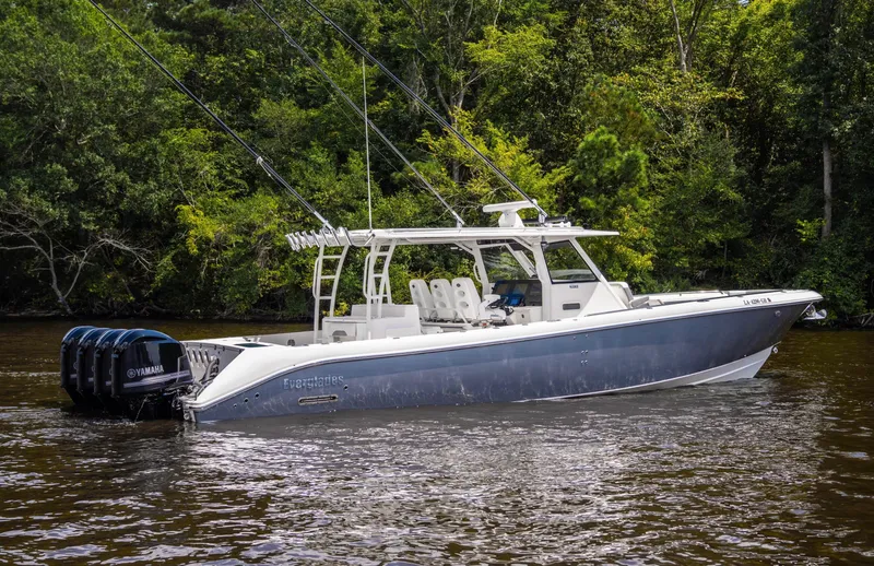  Yacht Photos Pics 2018 Everglades 435 Center Console boat on a calm river, surrounded by lush greenery.