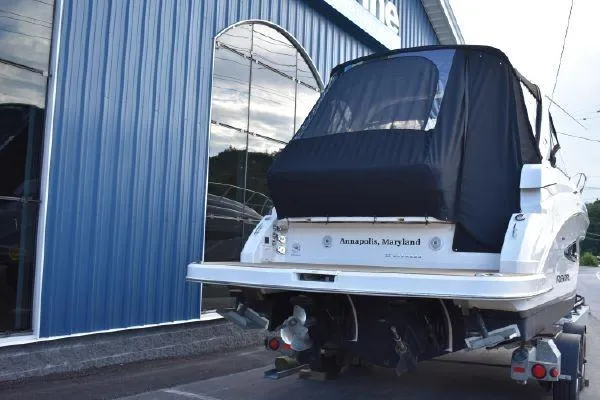  Yacht Photos Pics 2015 Regal 32 Express boat with cover, parked outside a blue building.