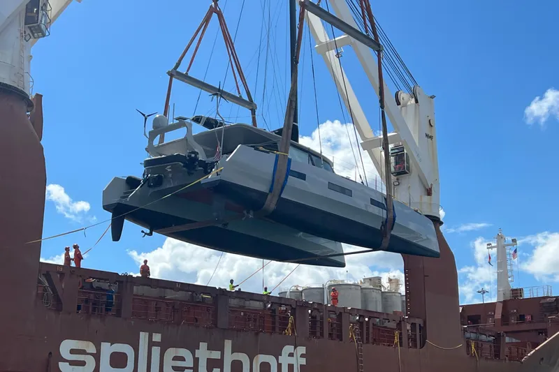 Crux Yacht Photos Pics 2017 Harvey Yachts 58 being lifted onto a cargo ship under a clear blue sky.