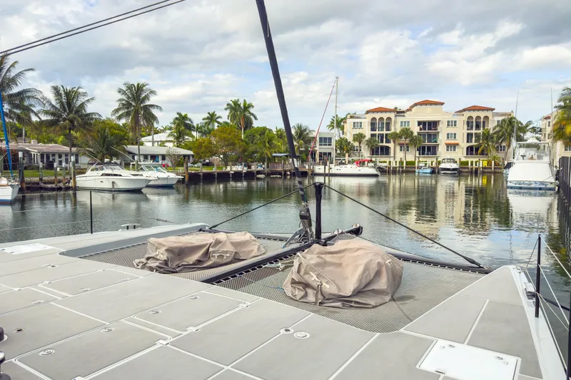 Crux Yacht Photos Pics Harvey Yachts 58 (2017) docked in a scenic marina with palm trees and luxury buildings.