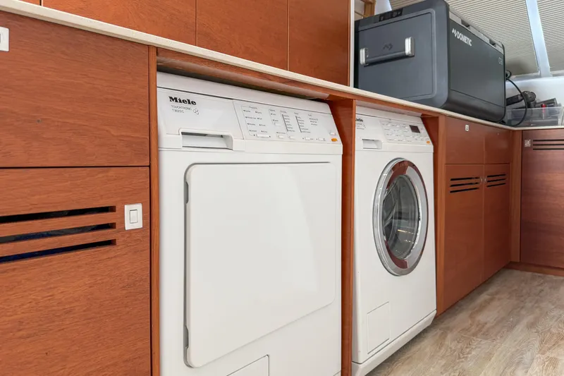 Crux Yacht Photos Pics Laundry area on a 2017 Harvey Yachts 58, featuring Miele appliances and wooden cabinetry.