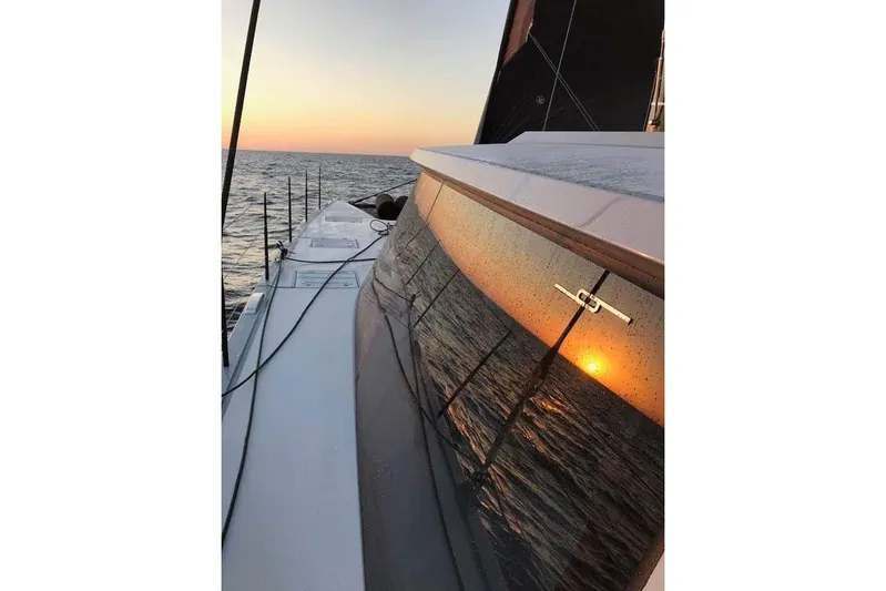 Crux Yacht Photos Pics 2017 Harvey Yachts 58 sailing at sunset, reflecting ocean and sun on windows.