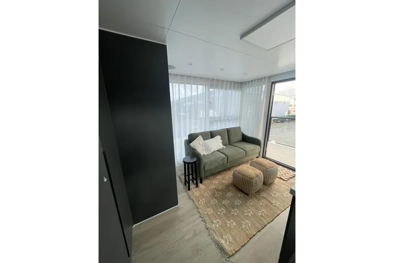  Yacht Photos Pics Modern houseboat interior with cozy sofa, poufs, and large windows, ALLHOUSE HB-1250, 2025 model.