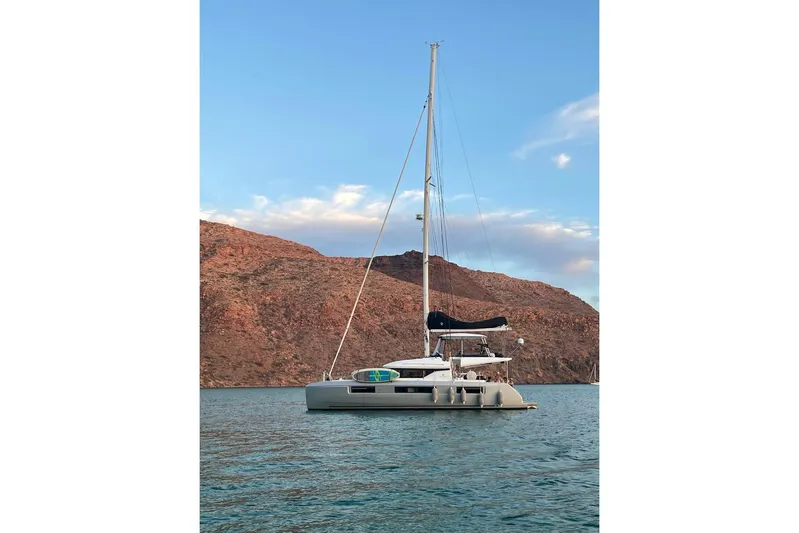  Yacht Photos Pics 2020 Lagoon 50 catamaran sailing near rocky coastline under blue sky.