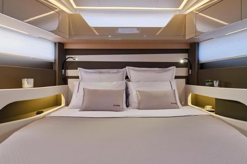  Yacht Photos Pics Luxurious cabin interior of 2025 Jeanneau DB/43 IB yacht, featuring elegant bedding and modern lighting.