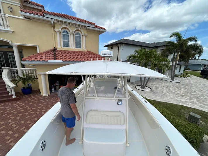  Yacht Photos Pics Man on 2002 Grady-White 306 Bimini boat near a house with palm trees.