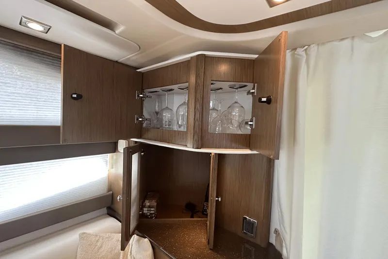  Yacht Photos Pics Interior of 2015 Meridian 441 Sedan with open wooden cabinets and glassware.