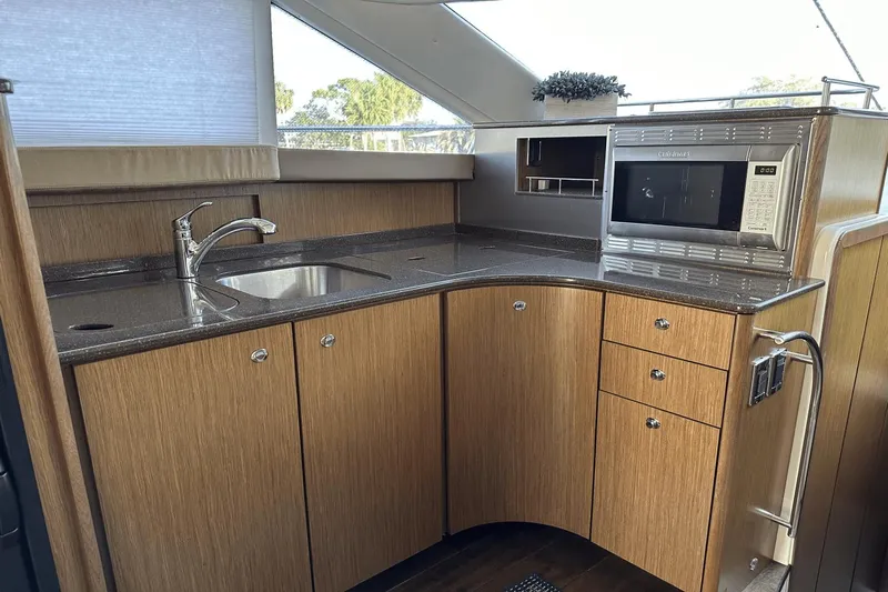  Yacht Photos Pics 2015 Meridian 441 Sedan yacht kitchen with wood cabinets, sink, and microwave.