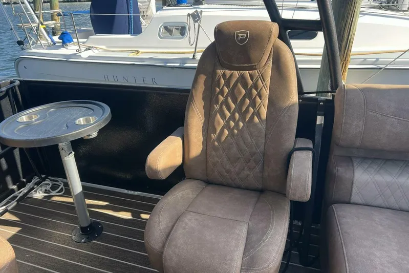  Yacht Photos Pics Luxurious seating on 2023 Premier 330 Escalante boat with table, docked near sailboat.