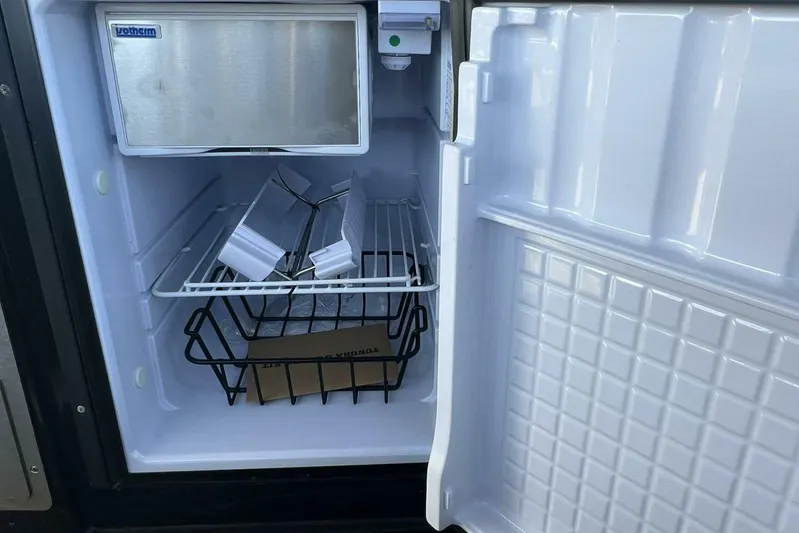  Yacht Photos Pics Open refrigerator in 2023 Premier 330 Escalante RV, featuring wire shelf and storage basket.