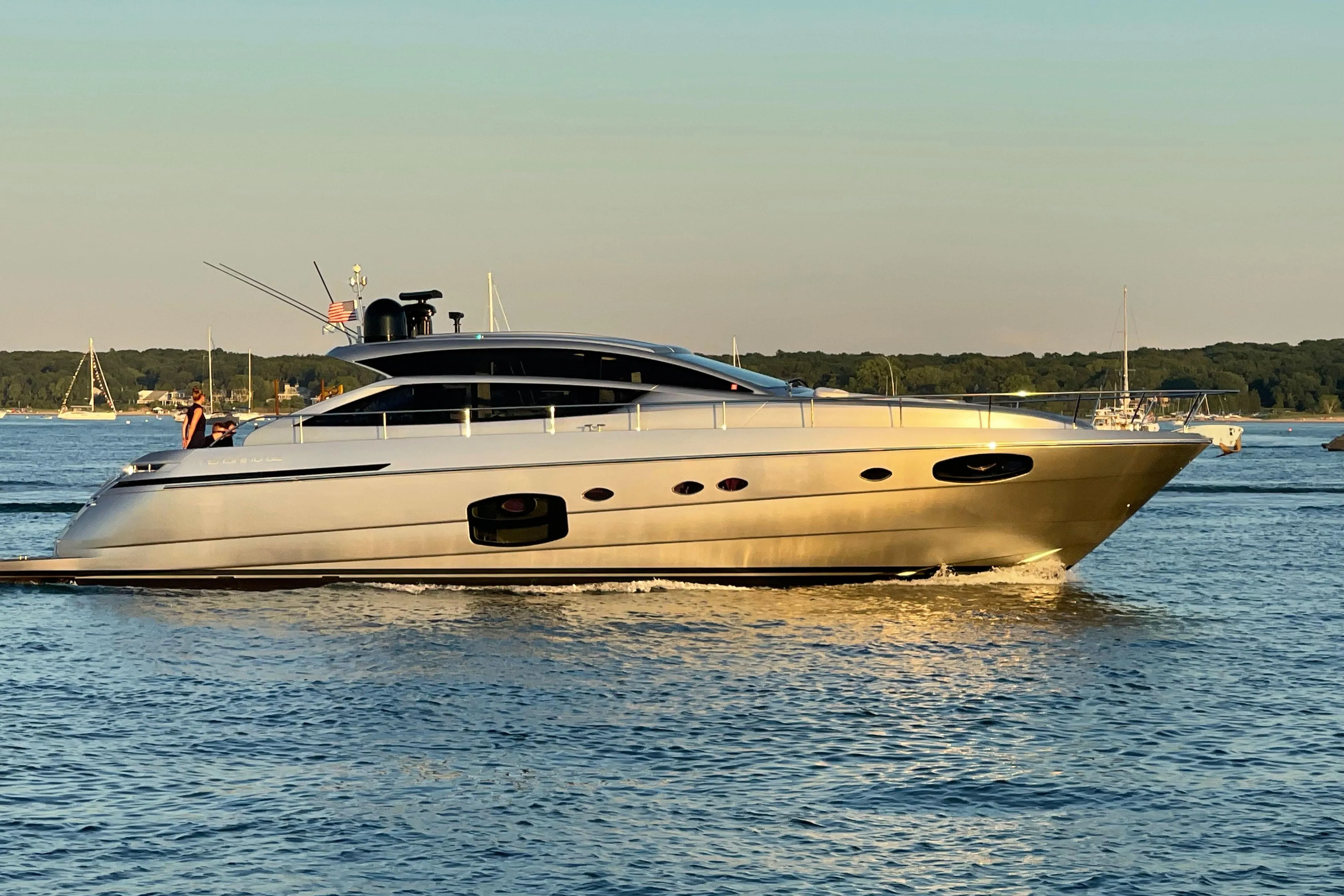 Luxurious 2015 Pershing 62' yacht cruising on calm waters at sunset.