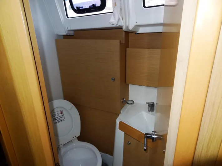 America Yacht Photos Pics 2018 Beneteau Oceanis 38 bathroom with toilet, sink, and wooden cabinetry.