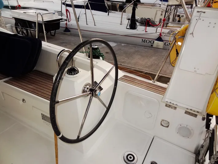 America Yacht Photos Pics Beneteau Oceanis 38 (2018) cockpit with steering wheel and docked sailboats in background.