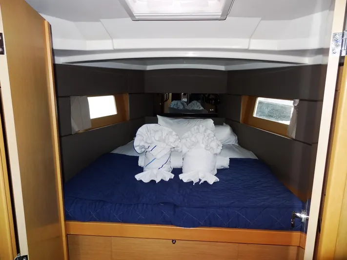 America Yacht Photos Pics Beneteau Oceanis 38 2018 cabin with bed, blue quilt, and towel sculptures.