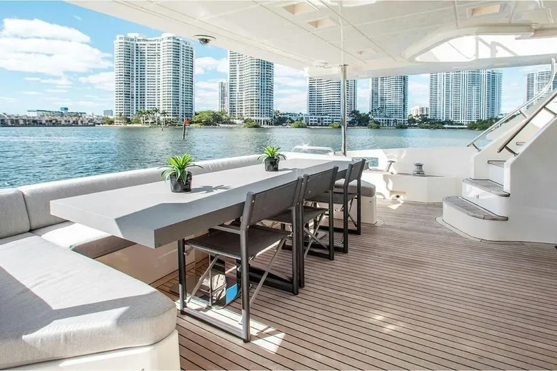 Bt2 Yacht Photos Pics Luxurious 2010 Azimut 95 yacht deck with dining area, overlooking waterfront cityscape.