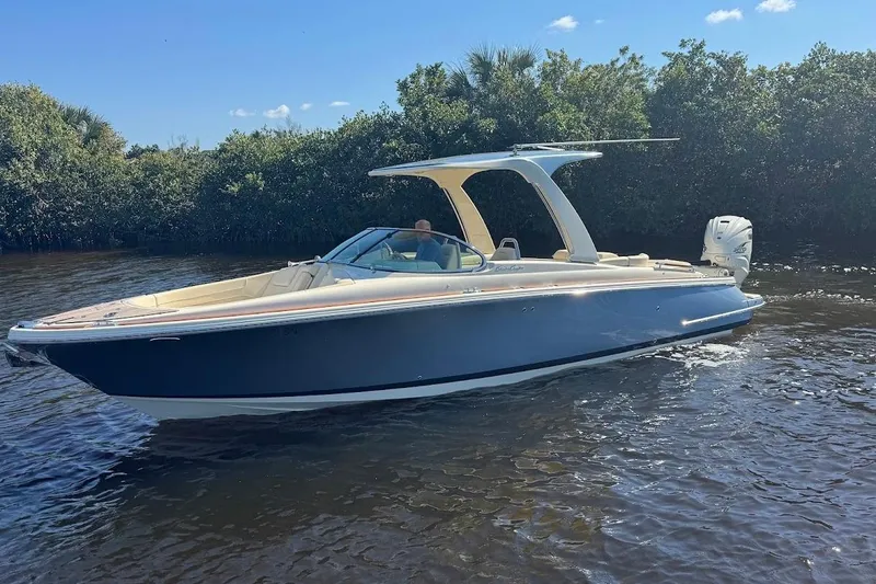  Yacht Photos Pics 2020 Chris-Craft Launch 28 boat on calm water, surrounded by lush greenery.