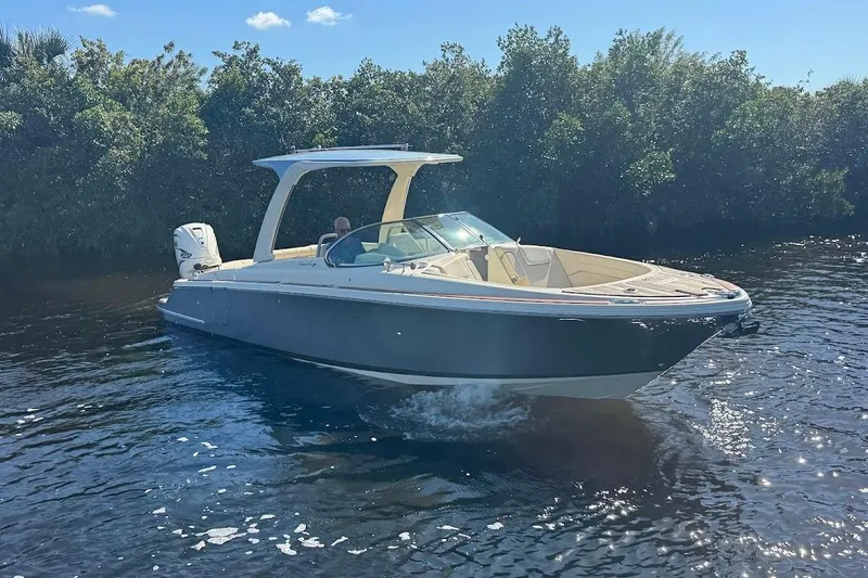  Yacht Photos Pics 2020 Chris-Craft Launch 28 boat cruising on a sunny day, surrounded by lush greenery.