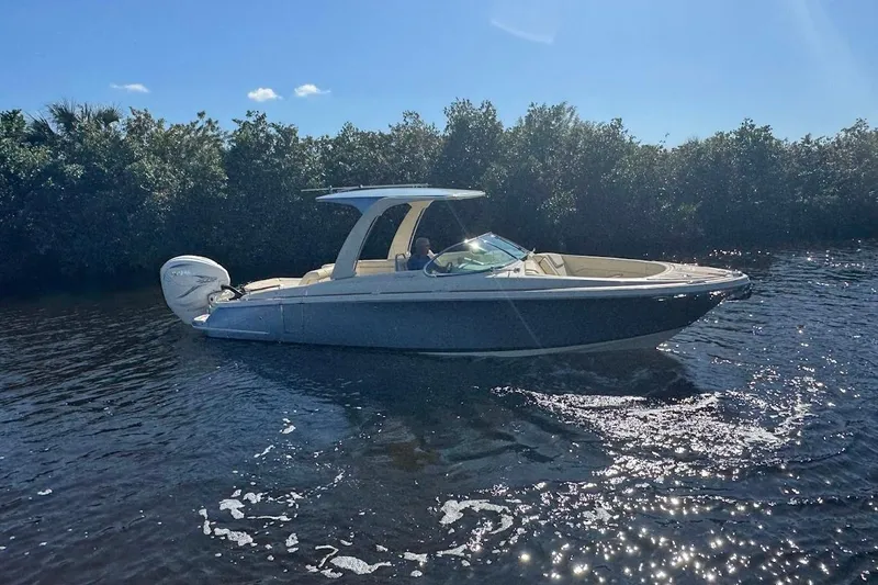  Yacht Photos Pics 2020 Chris-Craft Launch 28 boat cruising on a sunny day near lush greenery.