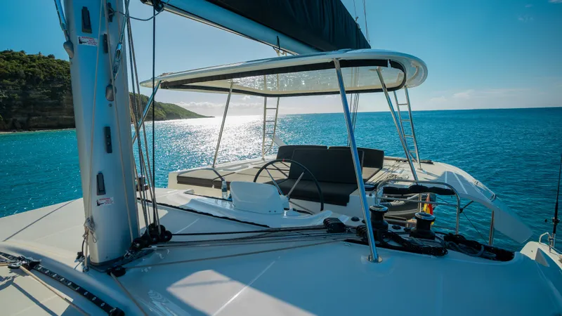 Infinity Yacht Photos Pics 2023 Lagoon 46 catamaran sailing on clear blue waters under a sunny sky.