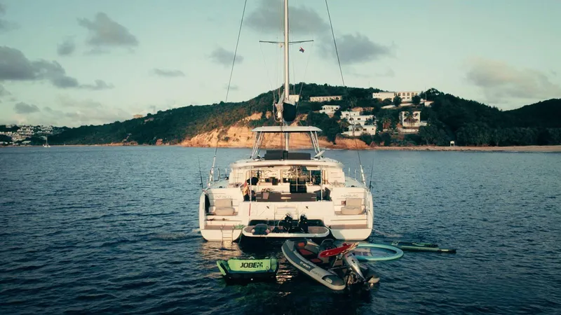 Infinity Yacht Photos Pics 2023 Lagoon 46 catamaran anchored near scenic coastline with paddleboards and kayak.