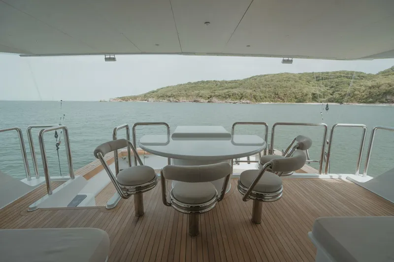 Aussie Rules Yacht Photos Pics Luxury yacht deck with seating, overlooking serene ocean and lush island, Oceanfast 87 Enclosed Bridge 1996.
