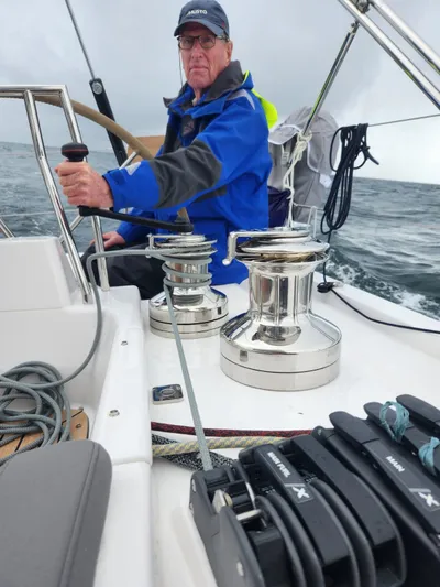 Yula Yacht Photos Pics Man steering 2024 X-Yachts Xc 47 sailboat in open sea, wearing blue jacket.