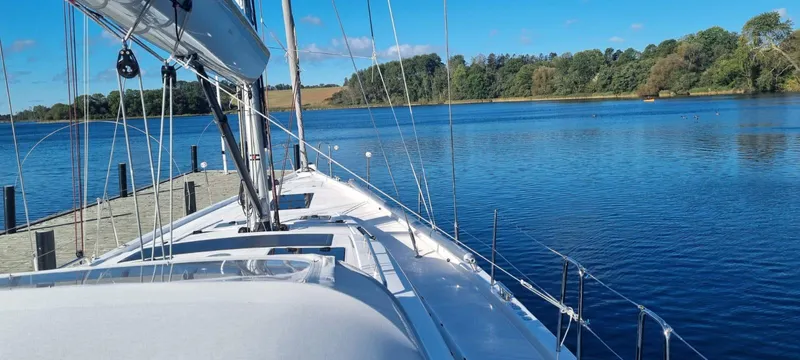 Yula Yacht Photos Pics 2024 X-Yachts Xc 47 sailboat docked on a serene lake with clear blue skies.