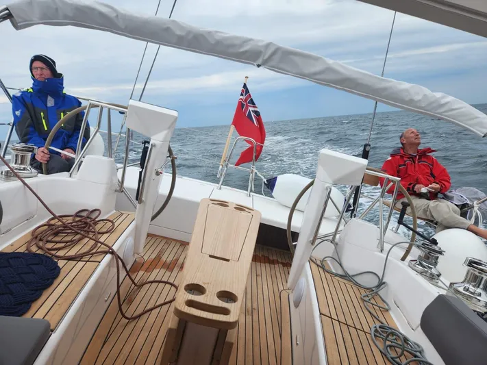 Yula Yacht Photos Pics 2024 X-Yachts Xc 47 sailing on open sea with crew, featuring teak deck and red ensign flag.