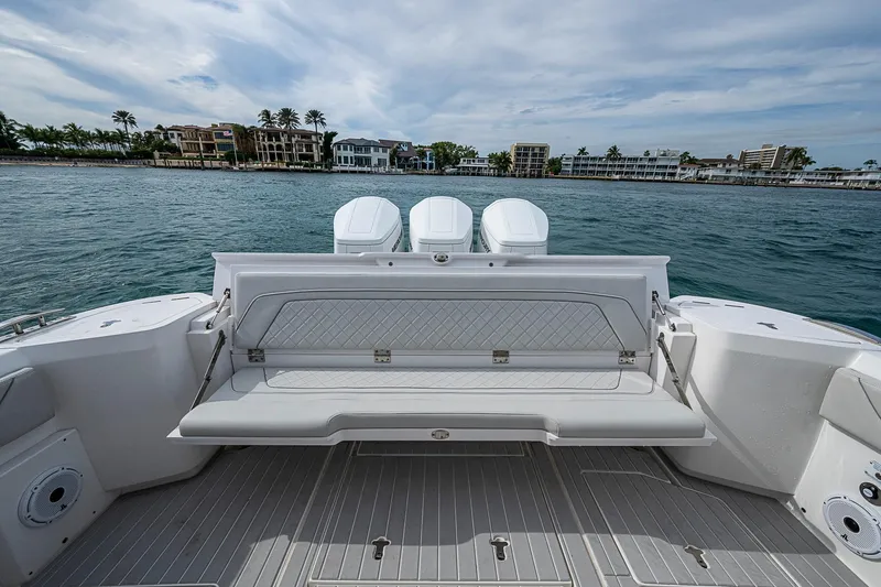  Yacht Photos Pics 2023 Intrepid 427 Nomad SE boat with luxurious seating, docked near waterfront homes.