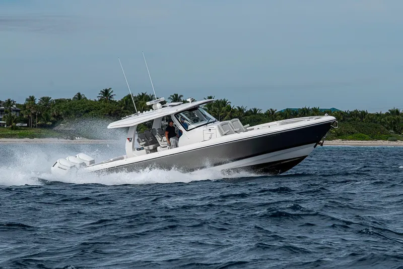  Yacht Photos Pics 2023 Intrepid 427 Nomad SE cruising on ocean near lush coastline.