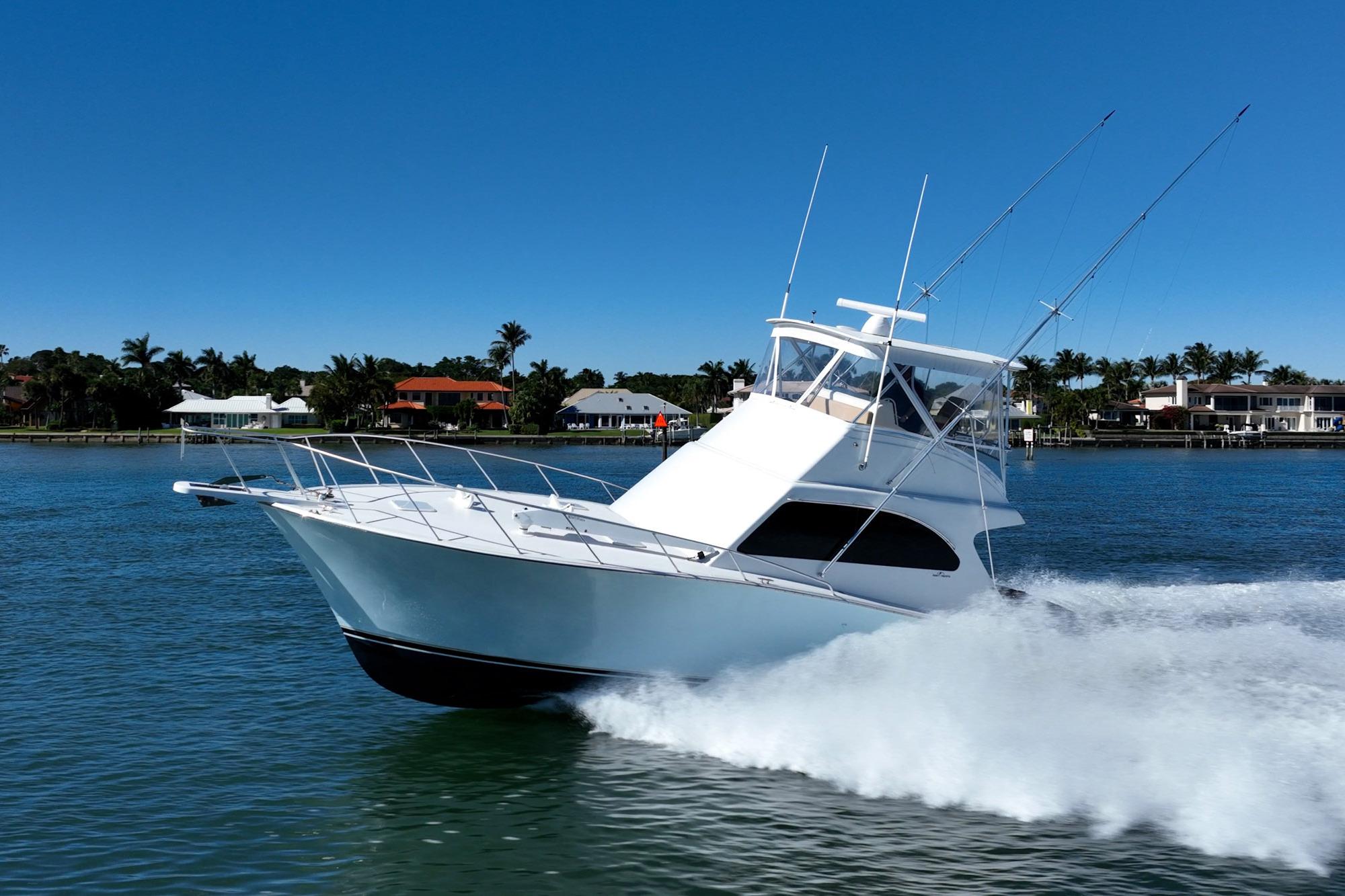 Sport fishing boat cruising on water, Post 42 model, 2001, with coastal homes in background.
