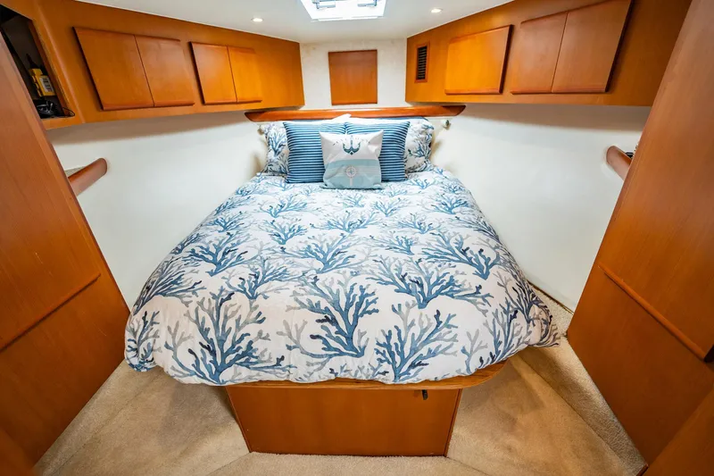 Business Yacht Photos Pics Cozy boat cabin with coral-patterned bedding, wooden cabinets, and soft lighting, Post 42 model, 2001.