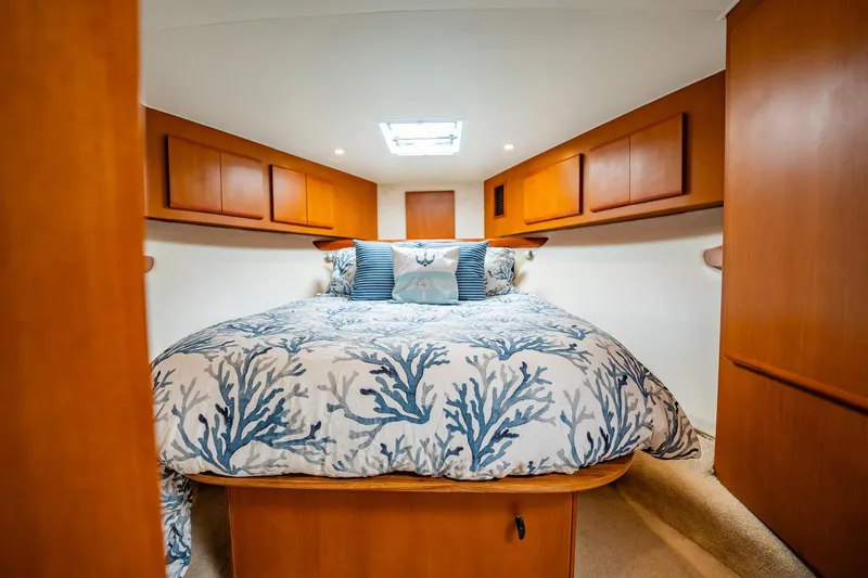 Business Yacht Photos Pics Cozy cabin bedroom in 2001 Post 42 yacht with nautical-themed bedding and wooden cabinetry.
