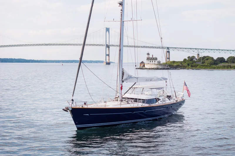 Ravenclaw Yacht Photos Pics Sailing yacht Oyster 82/08 (2007) on calm waters near a bridge and lighthouse.