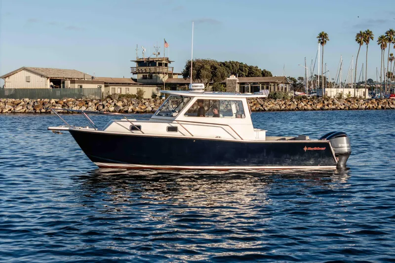 Caroline II Yacht Photos Pics 2021 NorthCoast 285 HT boat on calm water near marina and rocky shoreline.